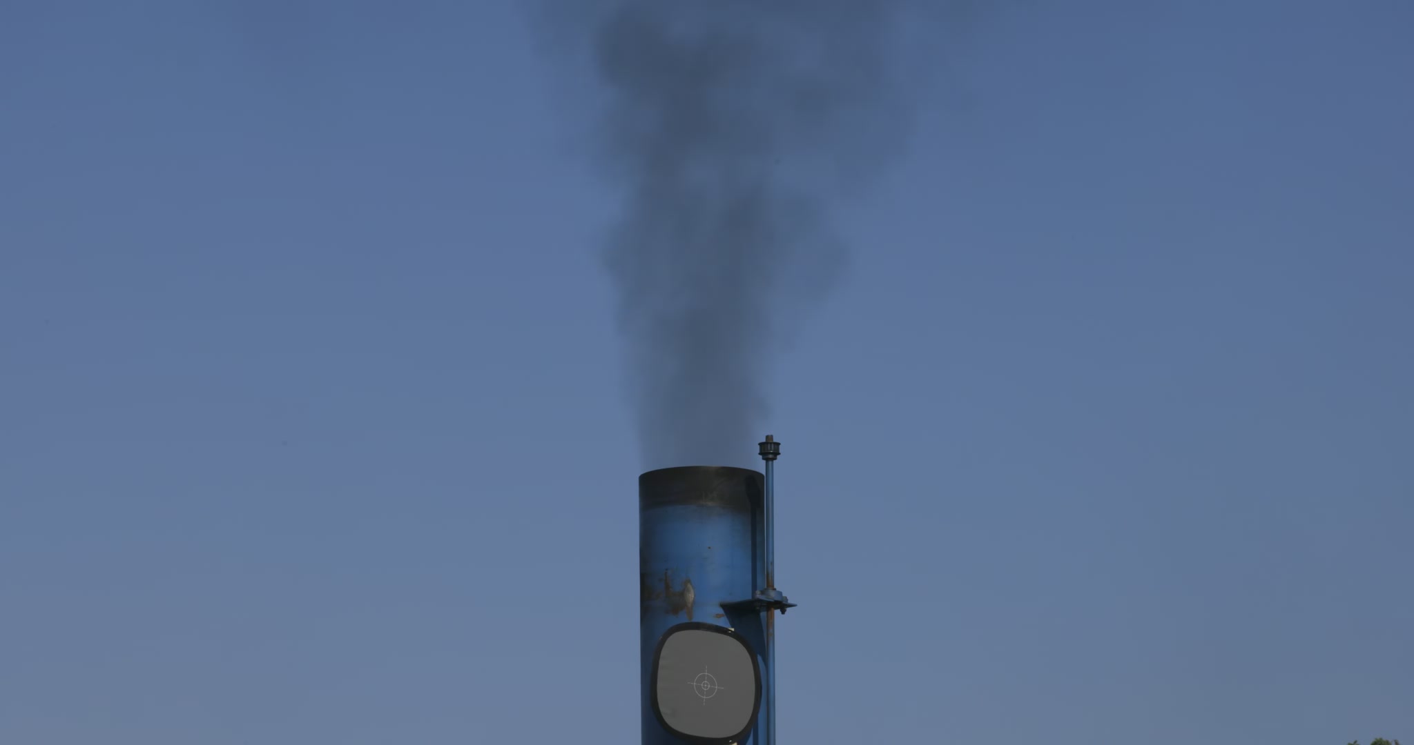 Black smoke plume against blue sky